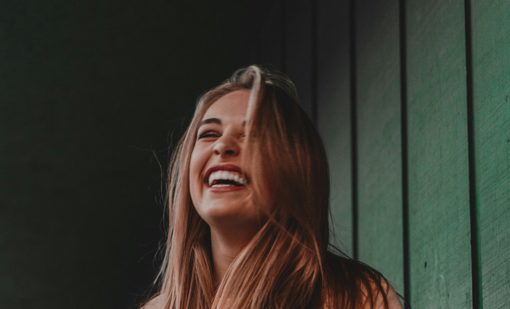 A woman laughing outdoors in warm light
