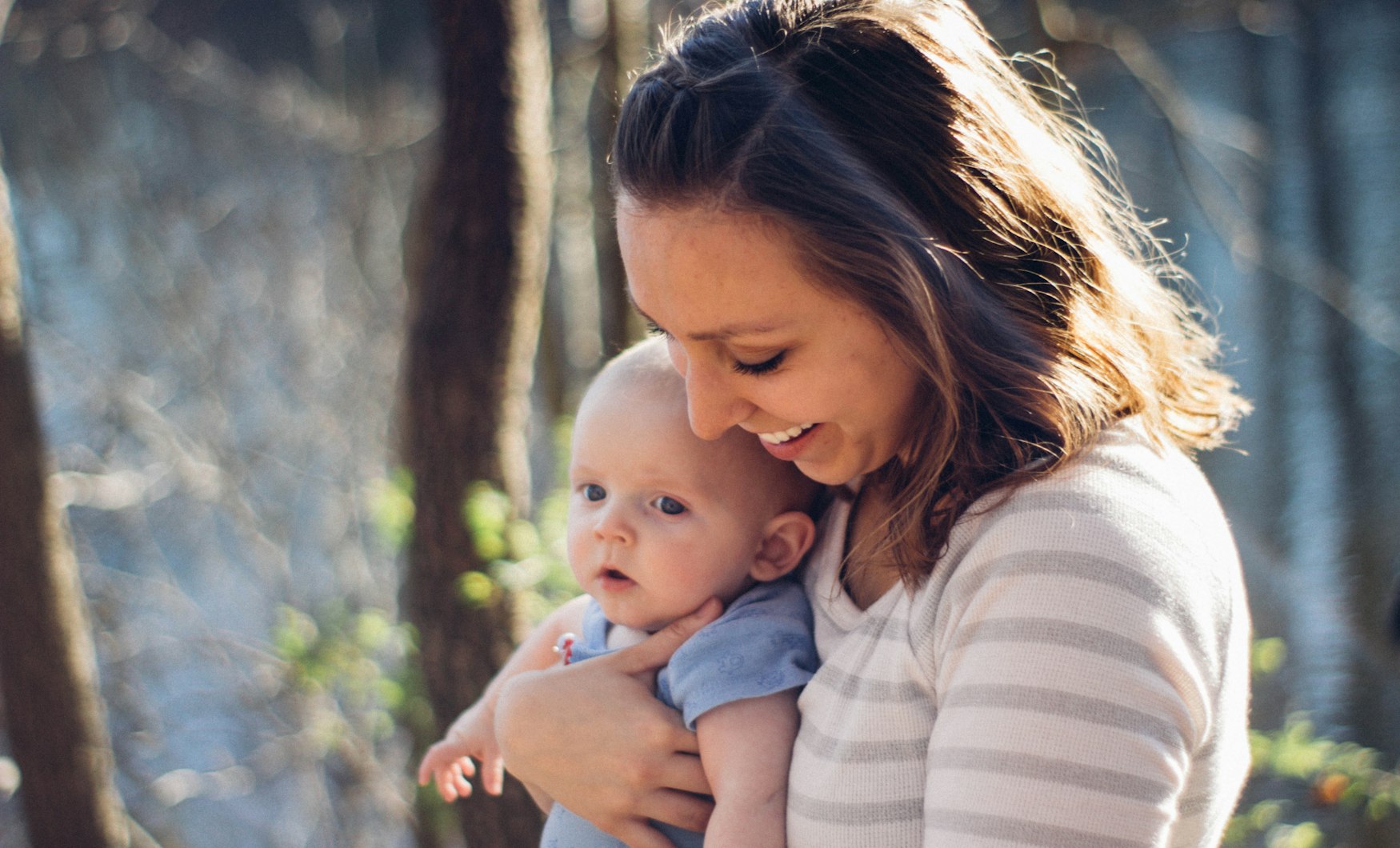 A mother holding her smiling baby outdoors