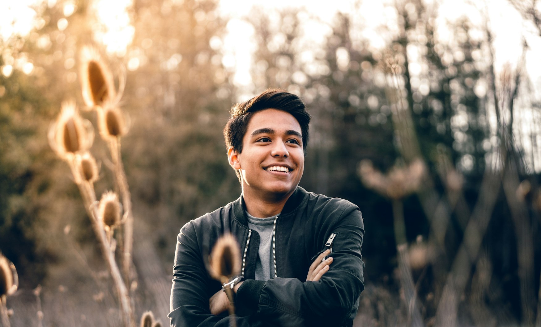 A man smiling among trees on a bright day